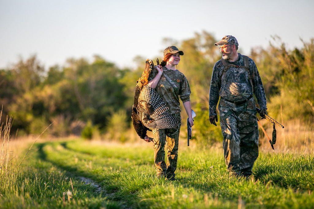 A father and daughter walk a trail while turkey hunting during spring in Nebraska.
